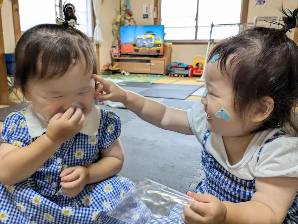 顔にシールを貼って遊ぶ女の子たち